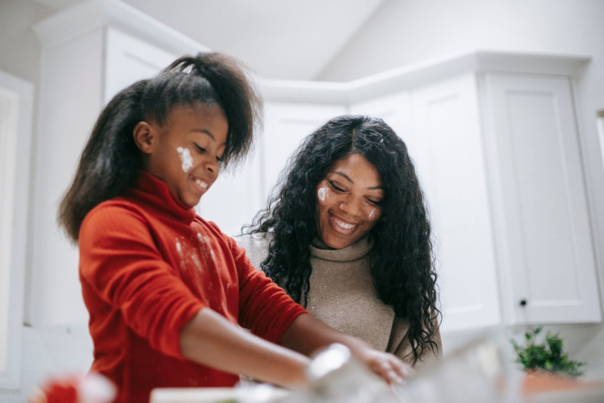 Happy dirty black girl with mother cooking in kitchen