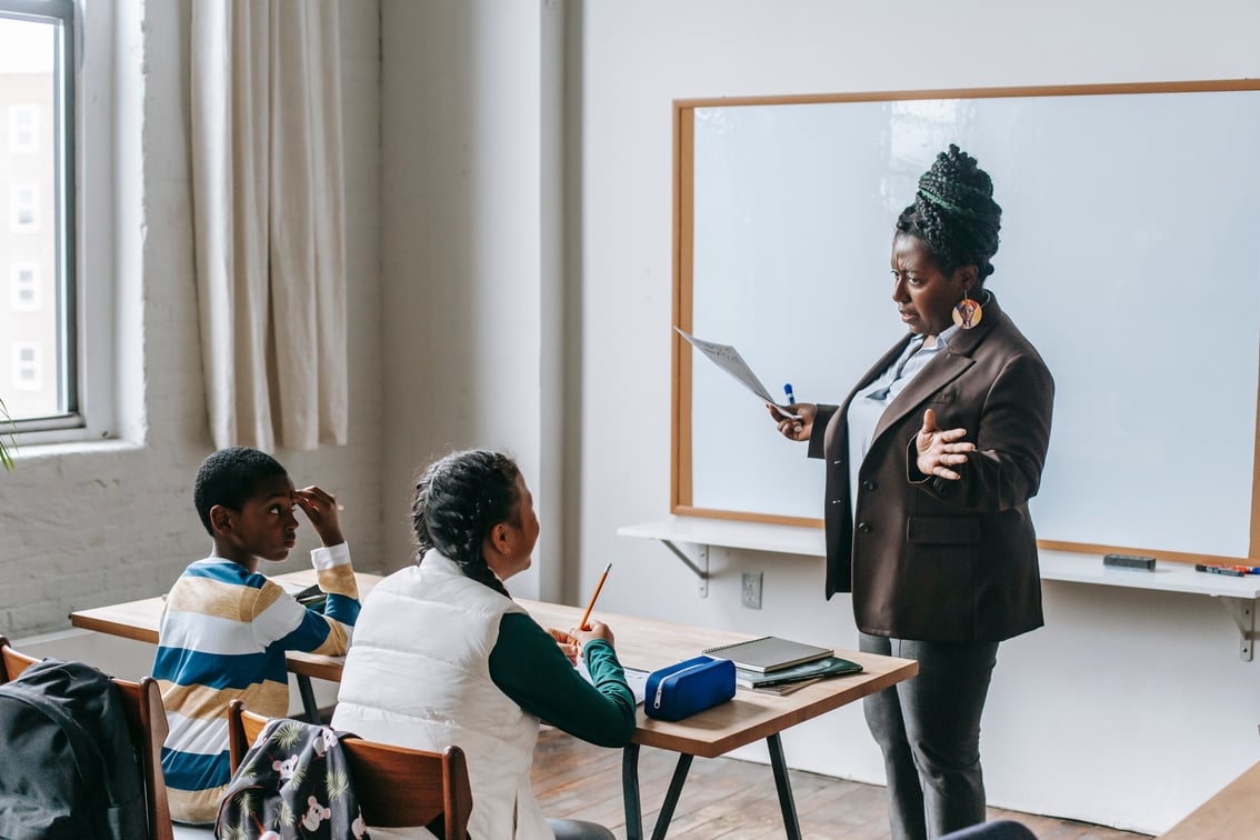 Black teacher explaining presentation to diverse elementary pupils